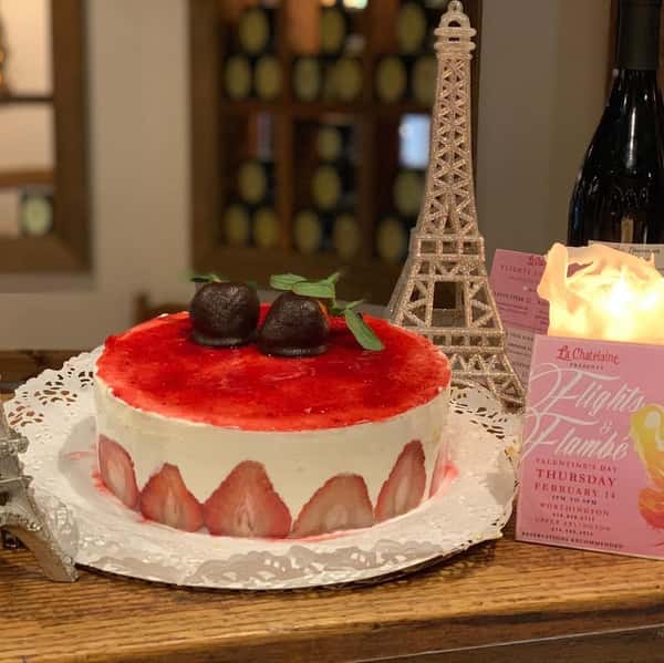 Strawberry cake topped with chocolate covered strawberries next to a mini eifel tower