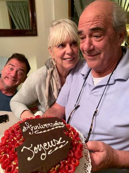 Family posing for picture while man is holding a cake