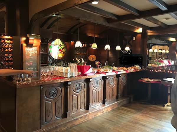 Counter top with glasses, coffee cups, bottles of champagne, and assortment of food in the bar area