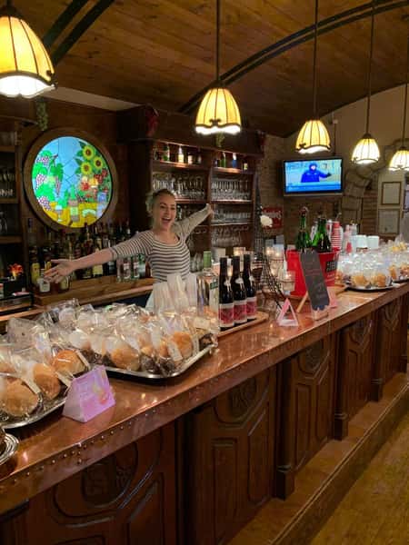 happy employee behind the counter that is topped with an assortment of pastries