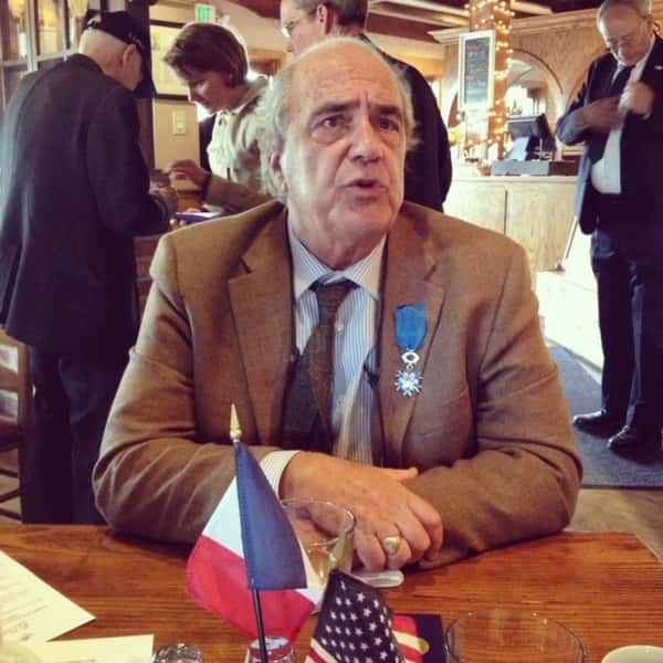man sitting at a a table wearing a suit with a medal