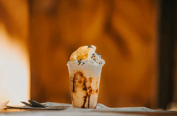 Scrumptious chocolate milkshake topped with whipped cream in a cup, perfect for a sweet treat.
