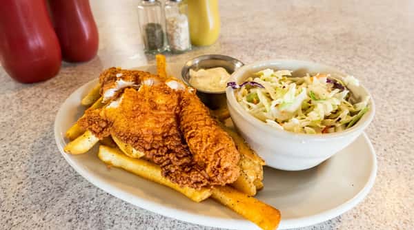 Fish and chips with coleslaw and tartar sauce on a white oval plate.