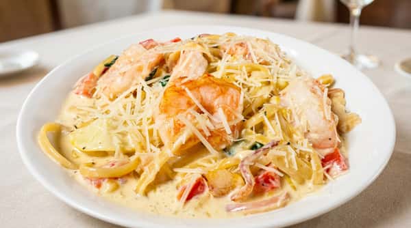 Creamy shrimp pasta with penne, tomatoes, and spinach, topped with shredded Parmesan cheese.