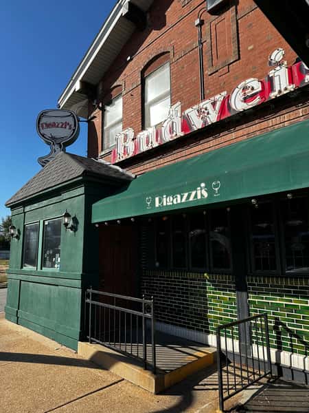 Close-up of Rigazzi's restaurant entrance with green awning, Budweiser sign, and signature frosted goblet logo.