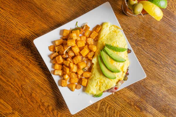 Breakfast omelet served with avocado slices and crispy breakfast potatoes on a white plate.