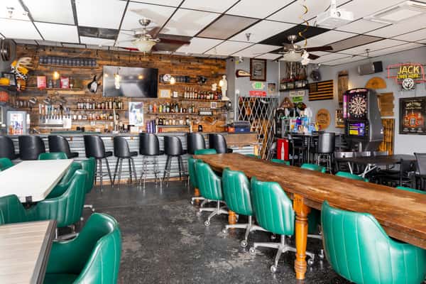 Long bar with green barstools, draft beer taps, and casual pub seating in a welcoming neighborhood tavern.