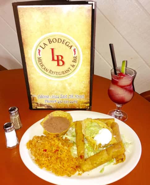 taquitoes with sides of rice, refried beans, sour cream, and guacamole, served with a mixed drink