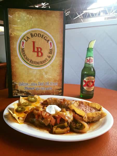 enchiladas and nachos topped with cheese, jalapenos and sour cream, served with a Dos Equis beer with a lime wedge