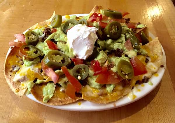 nachos with cheese, guacamole, sour cream, tomatoes and jalapenos