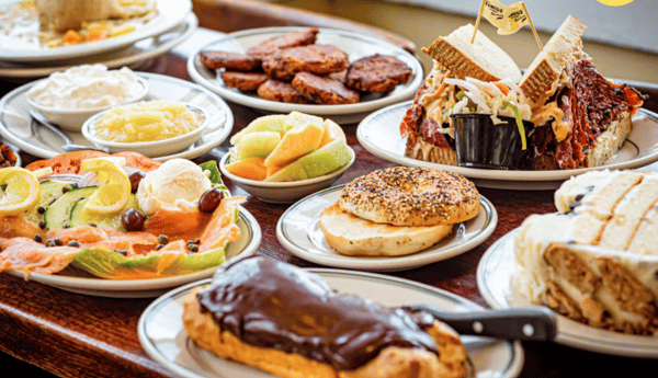 Deli brunch spread with bagels, blintzes, fruit, and pastries at Famous 4th Street Deli — kosher-style comfort food in Philadelphia.