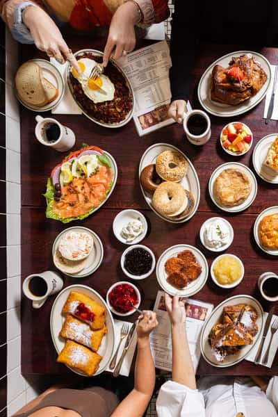Overhead view of Famous 4th Street Delicatessen breakfast spread with bagels, lox, French toast, and coffee — classic Jewish-style brunch in Philadelphia.
