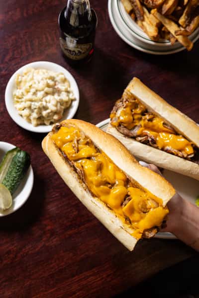 Philly cheesesteak sandwich served with creamy mac and cheese at Famous 4th Street Delicatessen.