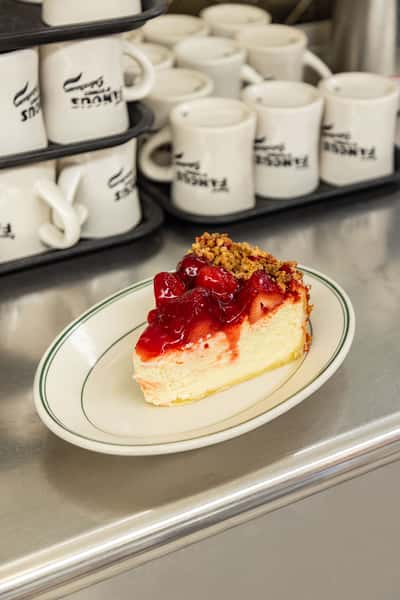 New York-style cheesecake with cherry topping at Famous 4th Street Delicatessen — classic kosher-style dessert.