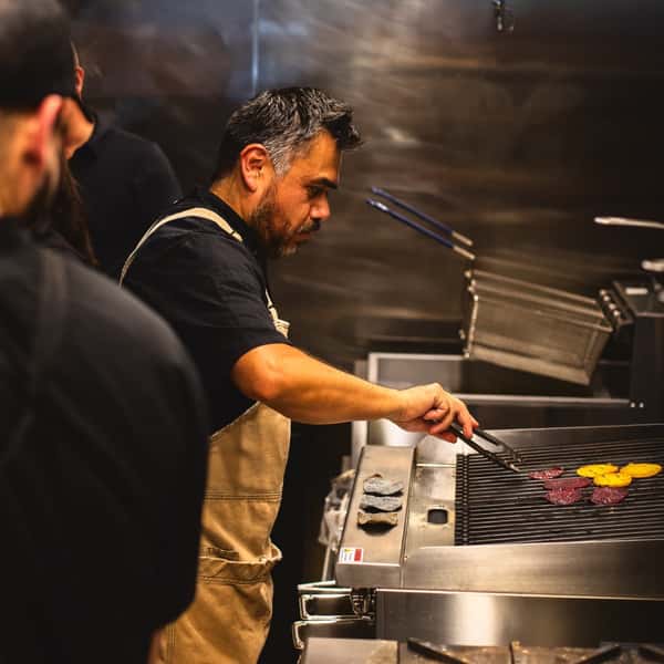 Chefs working in a dark, moody restaurant kitchen on fresh meals