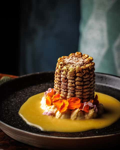 Moody interior with a saucy corn dish served on a wooden table