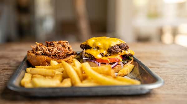 Cheeseburger with melted cheese, tomato, onion, and a side of french fries.