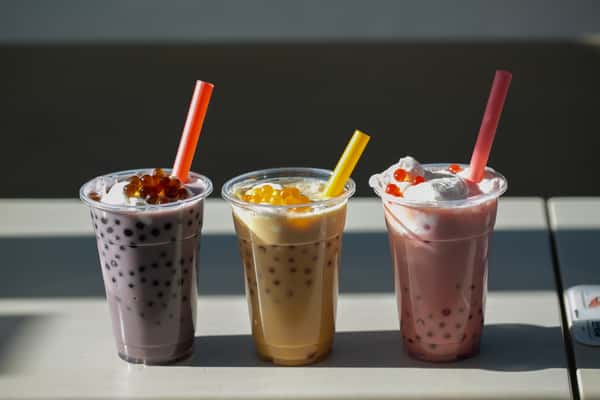 Here's a photo of some Poke Tea drinks. There are three drinks in plastic cups, each a different color: purple, yellow, and pink, each with boba pearls and a straw.