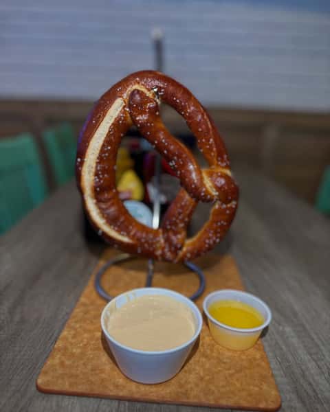 Warm jumbo soft pretzel served with creamy beer cheese dip and melted butter for a classic shareable appetizer.