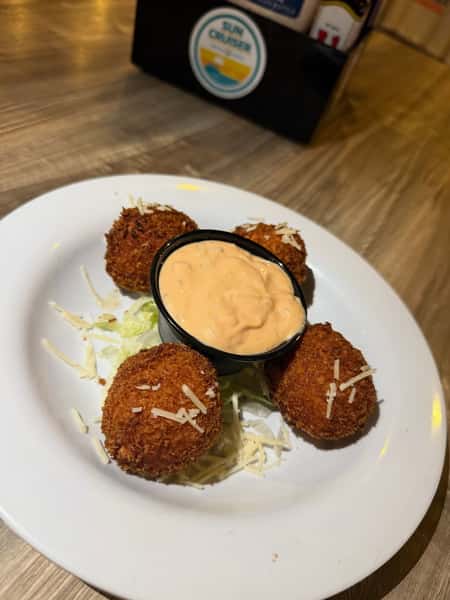 Crispy fried crab or seafood croquettes served with a creamy house dipping sauce and shredded Parmesan garnish.