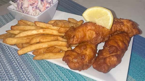 Plate of fried fish with French fries and a lemon wedge.