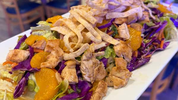 Grilled chicken salad with shredded cabbage, crispy tortilla strips, and mandarin oranges.