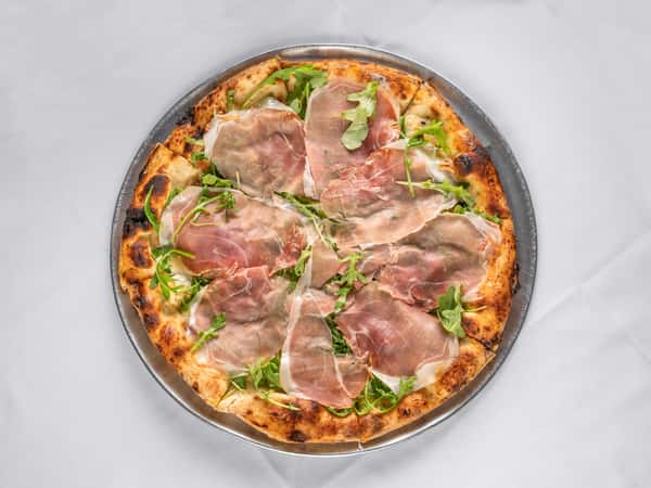 Overhead view of a gourmet pizza topped with fresh arugula and thinly sliced prosciutto on a crisp, wood-fired crust.