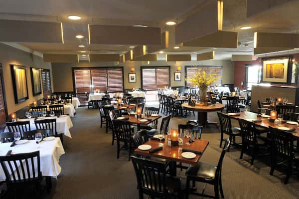 inside the dining room with tables, chairs and place settings