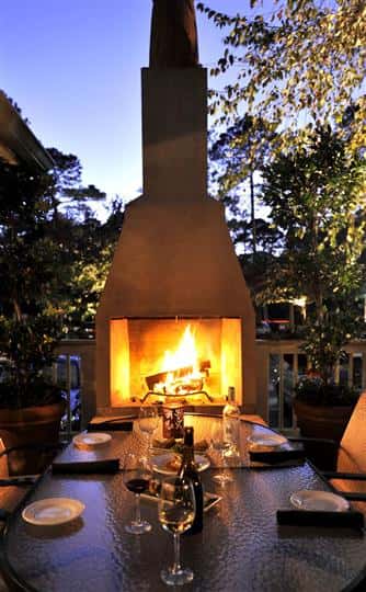 outdoor fireplace with table and 2 chairs in front