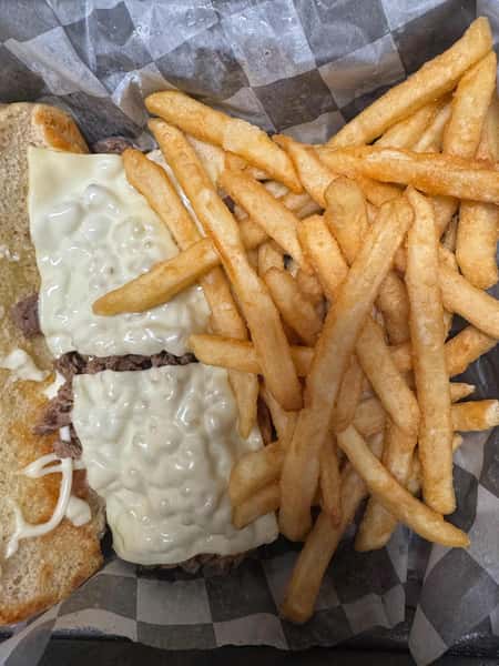 Open-faced cheesesteak sandwich topped with melted white cheese, served with a side of golden crinkle-cut fries in a black tray.