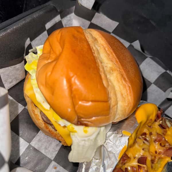 Cheeseburger with lettuce and a toasted bun, served alongside a loaded baked potato topped with melted cheese and bacon.