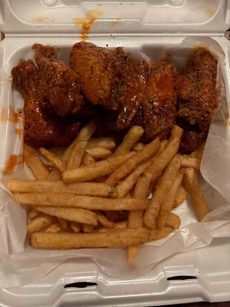 Takeout box with seasoned buffalo wings and a generous serving of golden, crispy French fries.