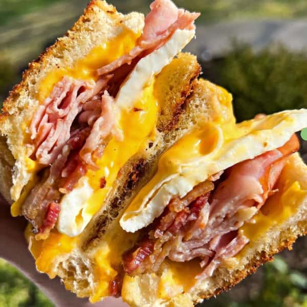 Breakfast sandwich loaded with ham, cheese, bacon, and eggs