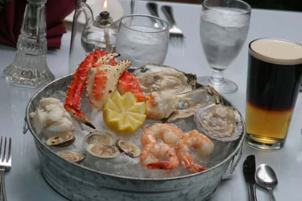 Chilled seafood bucket including lobster, oysters, and fresh shrimp with lemon