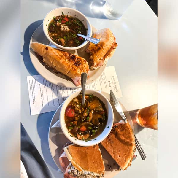Overhead view of savory mushroom soups and pressed, toasted sandwiches served at The Downing Bottles and Bites.
