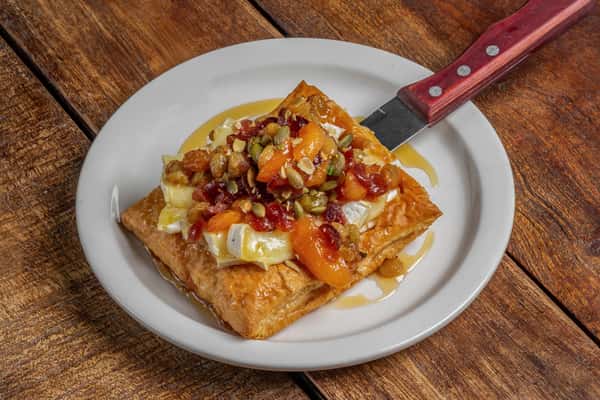 Golden baked Brie puff pastry tart with apricot and fruit preserves, drizzled with honey at The Downing Bottles and Bites.