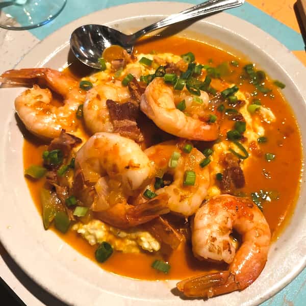 Classic shrimp and grits dish with rich orange gravy and green onions from The Downing Bottles and Bites.
