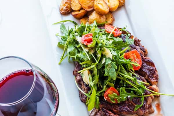 Salad on a platter with a side and a glass of wine