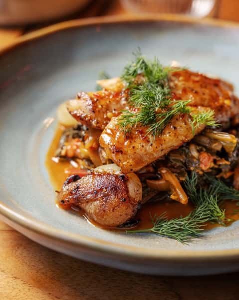 Pan-seared fish served over sautéed vegetables with roasted potatoes and fresh dill in a flavorful Southern-style entrée.