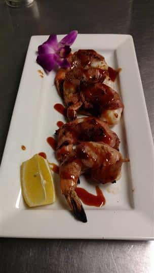 Shrimp drizzled in sauce with a lemon sauce on the side