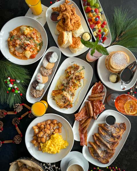 Assorted Holiday Brunch Items to include a variety of cookies, pancakes and syrup, shrimp and grits, biscuits, sausage & bacon, French toast and scrambled eggs with potatoes.