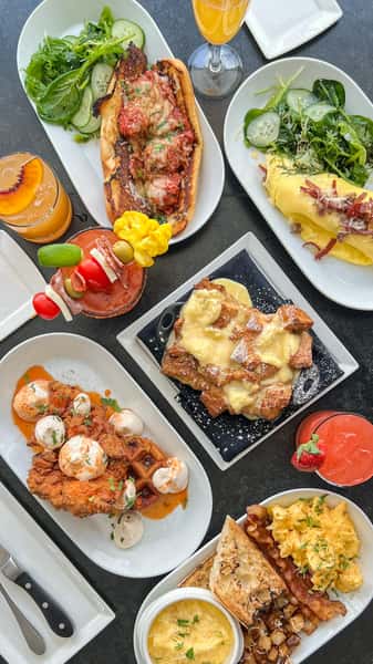 Tablescape with brunch items to include chicken & waffles, French toast, godfather omelet & brunch cocktails