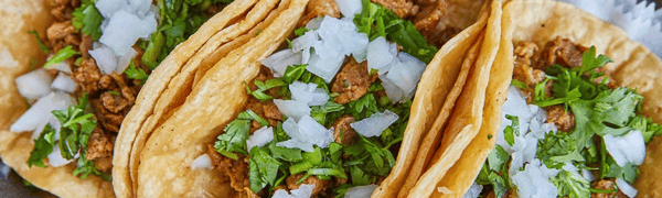 Close-up of carne asada street tacos on corn tortillas, topped with fresh chopped onions and cilantro, highlighting authentic Mexican street food flavor.