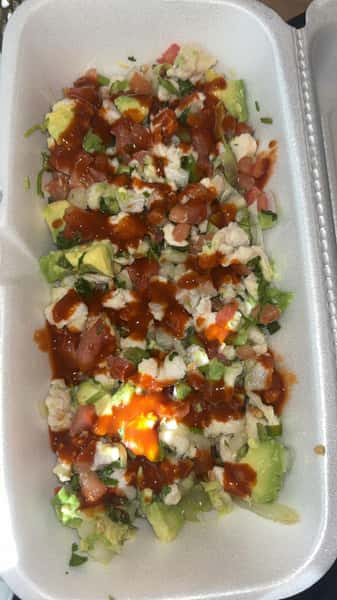 Fresh seafood ceviche in a takeout container, loaded with shrimp, avocado, tomato, onion, and cilantro, topped with tangy red salsa.