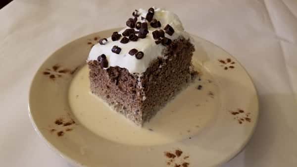 A soaked sponge cake topped with whipped cream and chocolate curls
