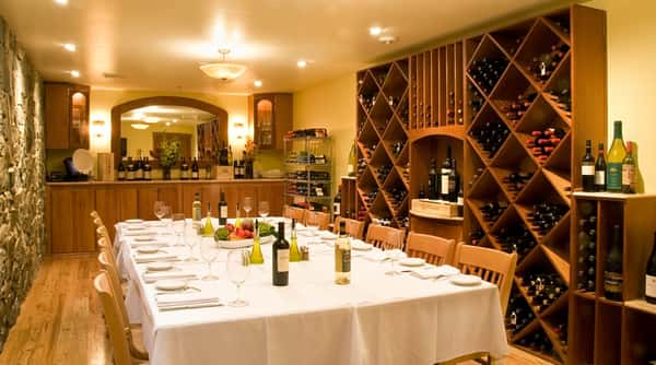 Restaurant private dining room with a long table set for a meal, flanked by large wine racks filled with bottles.