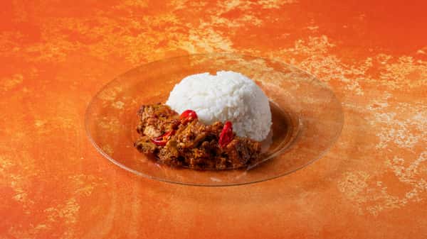 Traditional Malaysian rice plate with white rice, spicy sambal, and flavorful meat side dishes served on a warm orange backdrop.