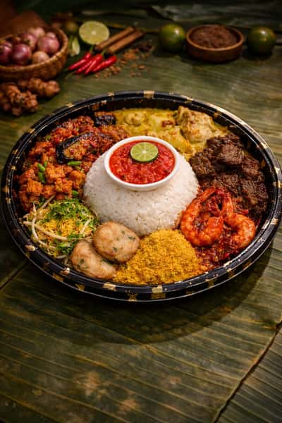 Traditional nasi ambeng platter for two with coconut rice, sambal, fried chicken, beef rendang, vegetables, and classic Malaysian side dishes.