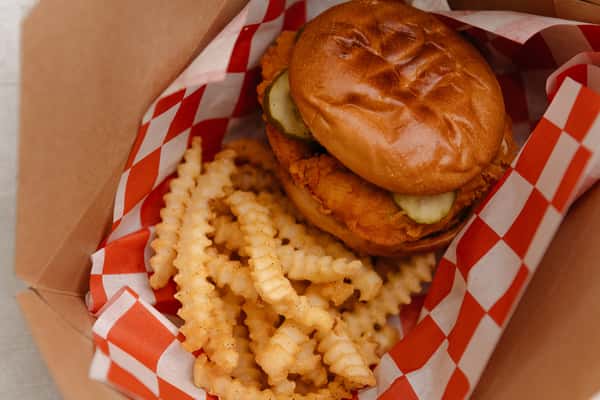 Chicken sandwich served in a takeout basket with crinkle cut fries.