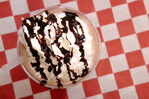 Chocolate milkshake topped with whipped cream and chocolate drizzle.